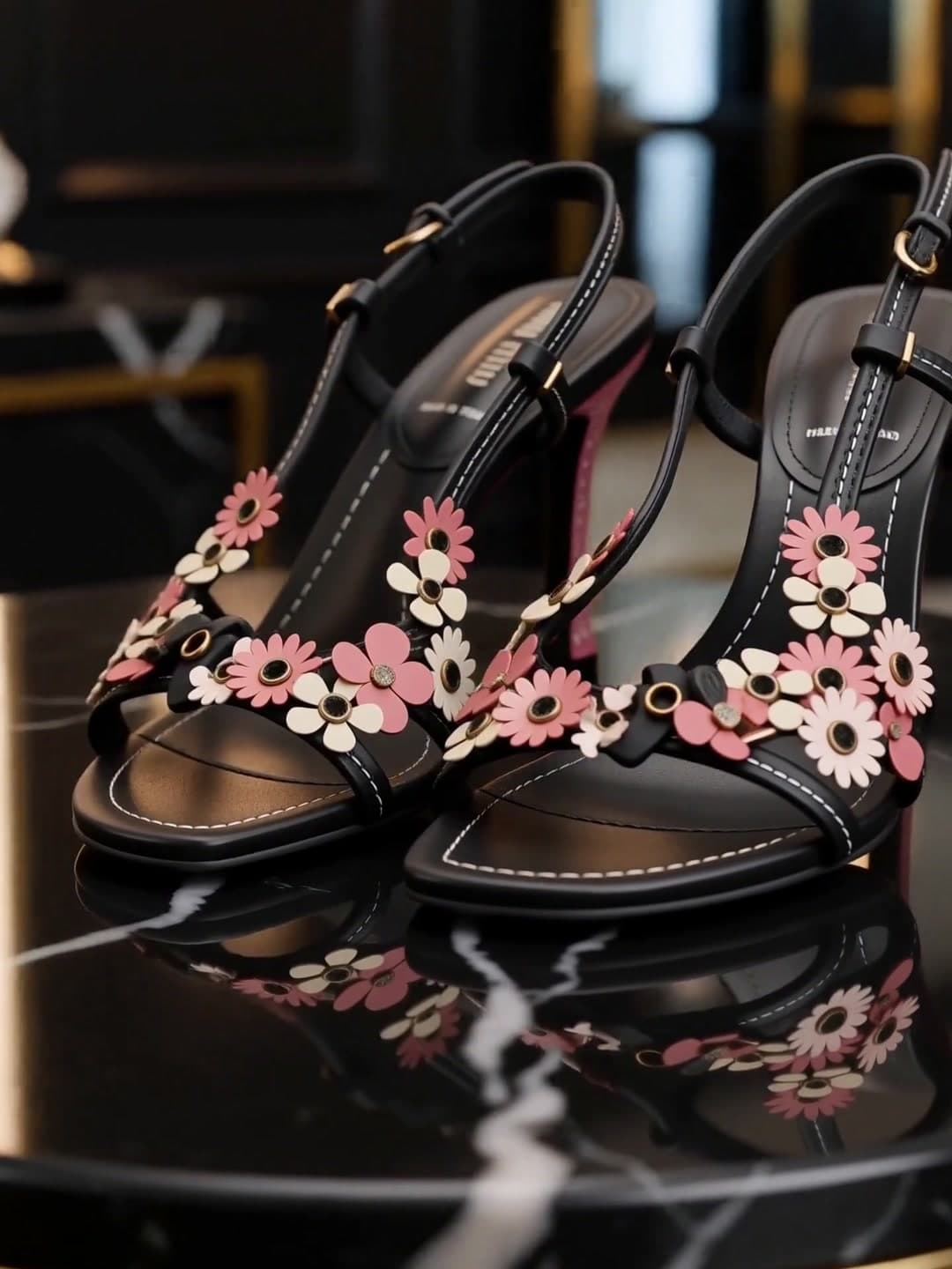 Floral appliqué sandals on black marble beneath an arched mirror